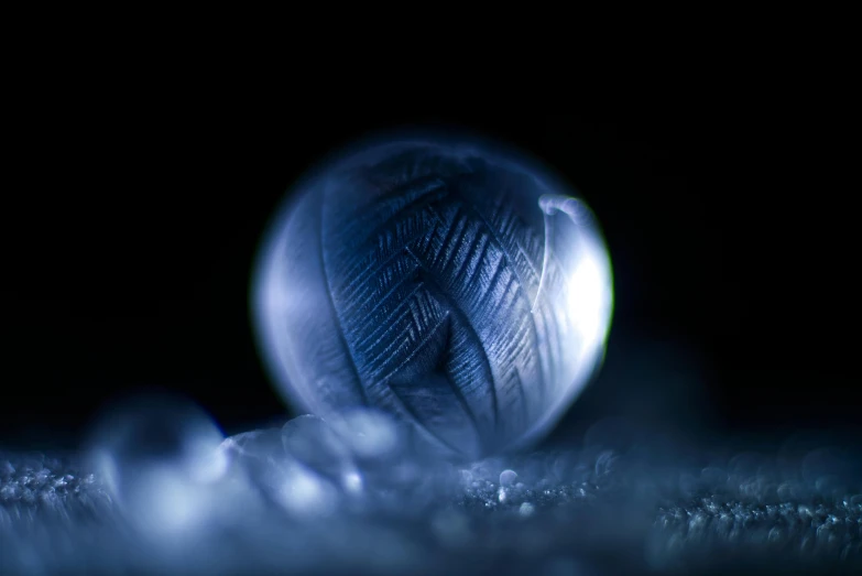 a ball of yarn sitting on top of a pile of snow, a macro photograph, by Adam Marczyński, art photography, blue translucent resin, moonstone, glowing veins of white, froz