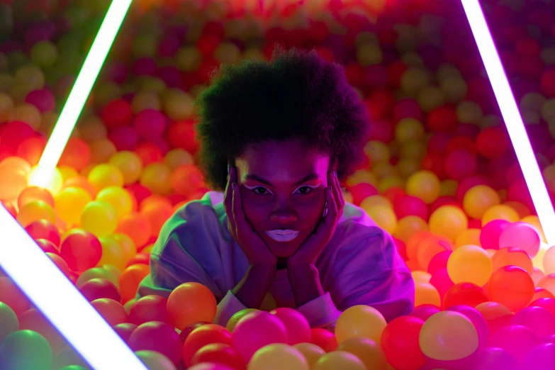 a person laying in a ball pit with neon lights, pexels contest winner, afrofuturism, black young woman, infinity mirror, adut akech, promo still
