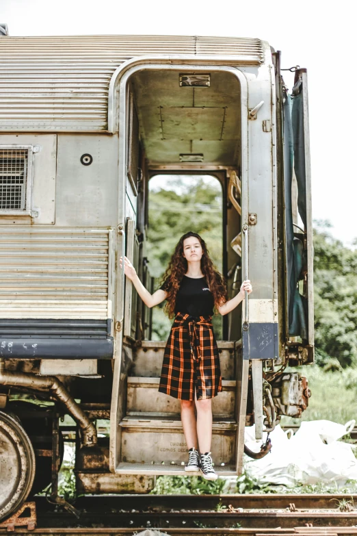 a woman standing in the doorway of a train car, a portrait, pexels contest winner, plaid skirt, 2 0 yo, ( ( ( kauai ) ) ), 15081959 21121991 01012000 4k