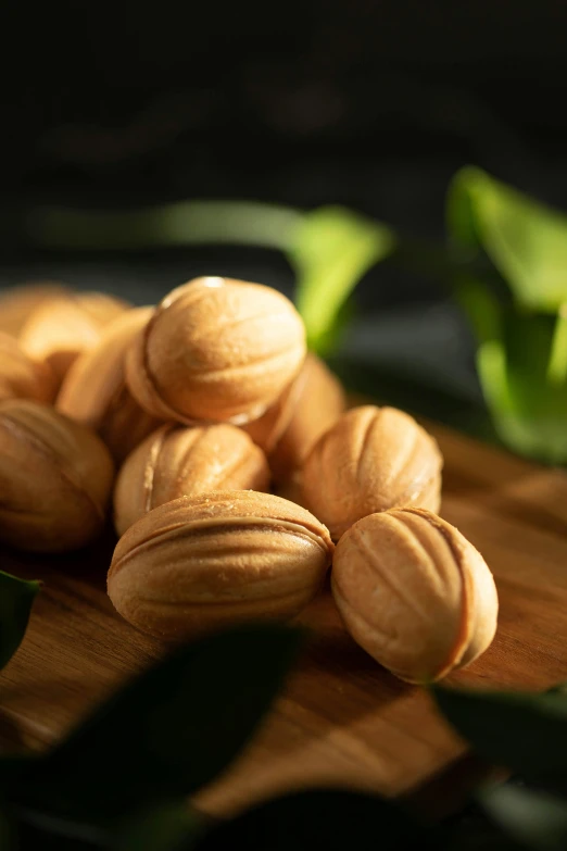 a pile of nuts sitting on top of a wooden cutting board, in front of a black background, lush surroundings, mint, wrinkly