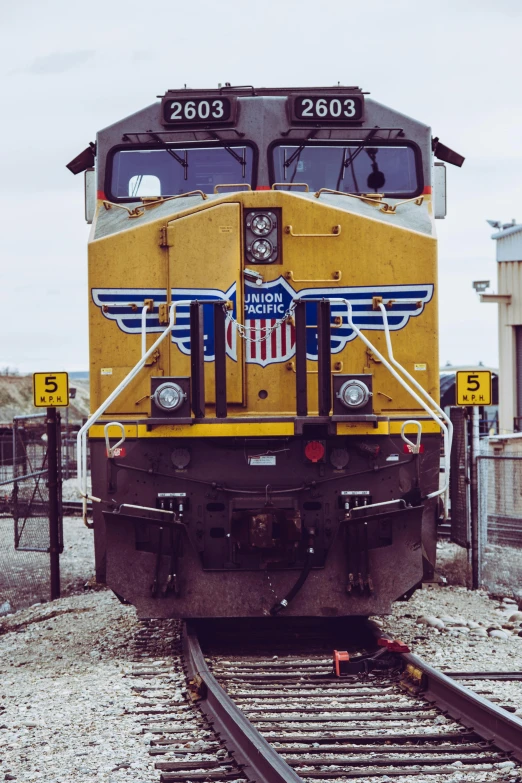 a yellow train traveling down train tracks next to a building, a portrait, engines, up close, instagram picture, usa