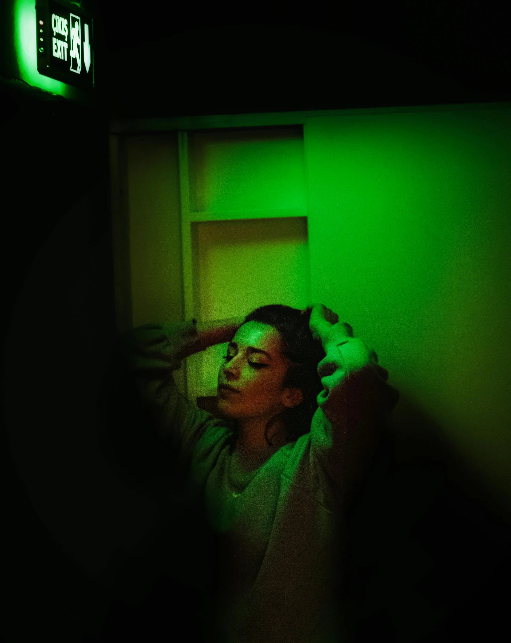 a woman in a dark room with a green light, inspired by Elsa Bleda, happening, instagram picture, green lantern, you are lost in the backrooms, rgb wall light