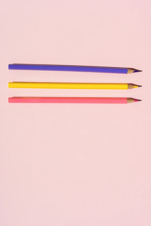 three pencils sitting next to each other on a pink surface, an album cover, by Doug Ohlson, trending on pexels, yellow purple, 15081959 21121991 01012000 4k, medium: colored pencil, multicolor
