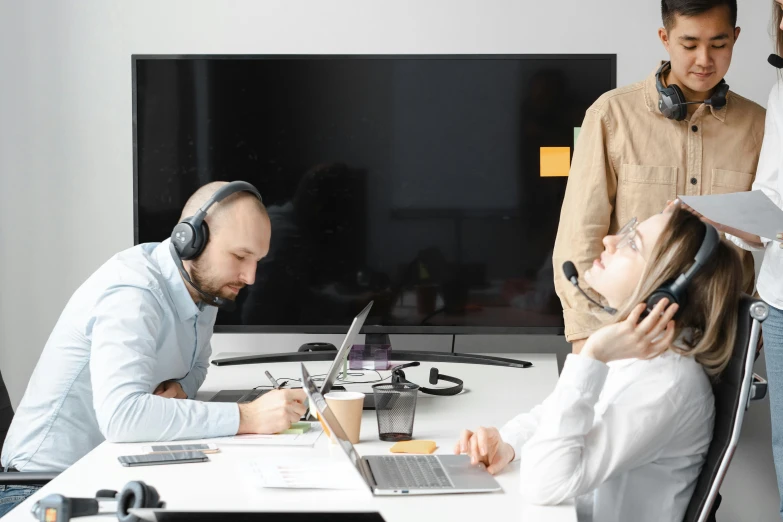 a group of people sitting around a table with laptops, by Sebastian Vrancx, pexels contest winner, hurufiyya, wearing headset, medium shot of two characters, working in a call center, blank