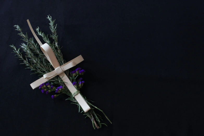 a cross on top of a bunch of flowers, inspired by Magdalene Bärens, unsplash, floggers, papyrus, on a black background, lavender