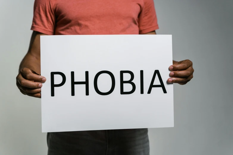 a man holding a sign that says phobia, trending on pexels, profile pic, depression, album art, worry