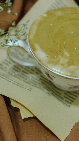 a cup of soup sitting on top of a napkin, a picture, unsplash, low quality photo, thumbnail, cappuccino, on old paper