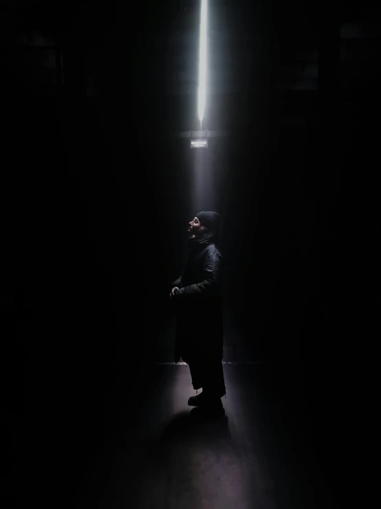 a man sitting in the middle of a dark room, an album cover, by Adam Marczyński, unsplash contest winner, light and space, orthodox cyberpunk, standing under a beam of light, profile image, instagram picture