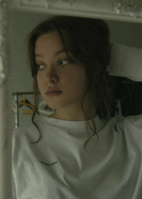 a woman brushing her hair in front of a mirror, inspired by Elsa Bleda, unsplash, realism, in tshirt, screenshot from a movie, portrait sophie mudd, in hospital bed