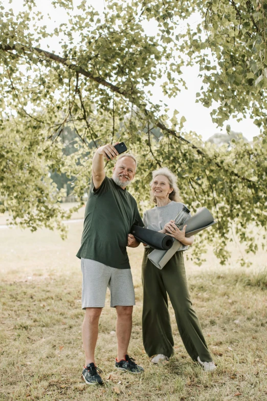 a man and a woman standing under a tree, taking selfies, portrait of hide the pain harold, flatlay, environment