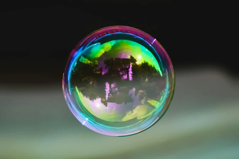 a soap bubble sitting on top of a table, rainbow reflection, shot with sony alpha 1 camera, multicolored, round-cropped