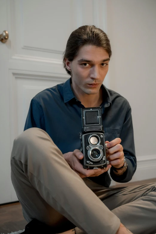 a man sitting on the floor holding a camera, by Mathias Kollros, lovingly looking at camera, xqc, alexandre chaudret, mid shot portrait