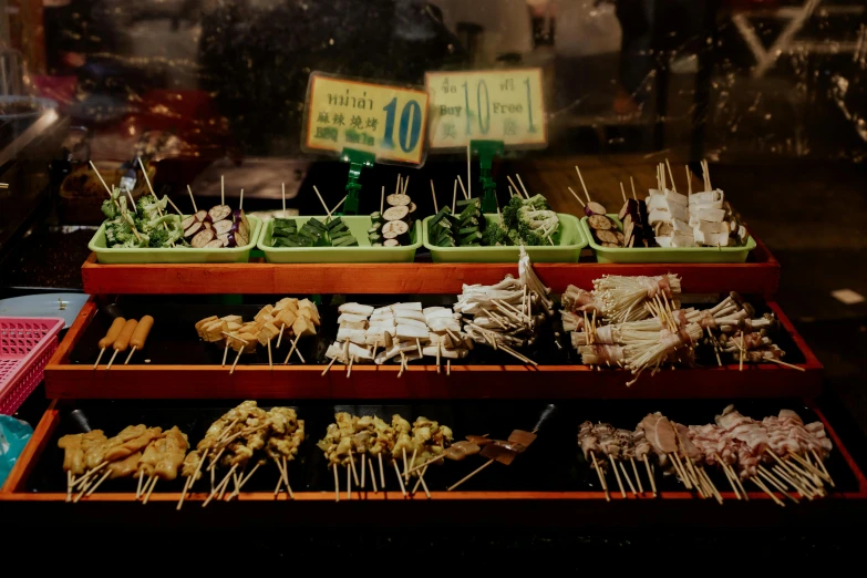 a display case filled with lots of different types of food, unsplash, mingei, skewer, background image, night time, green