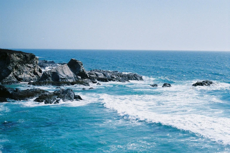 a large body of water next to a rocky shore, pexels contest winner, blue tinted, oceanside, pch, slide show