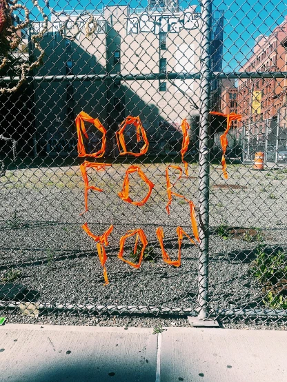 a chain link fence with graffiti written on it, an album cover, by Derf, reddit, orange neon, 💣 💥💣 💥, please do your best, ny