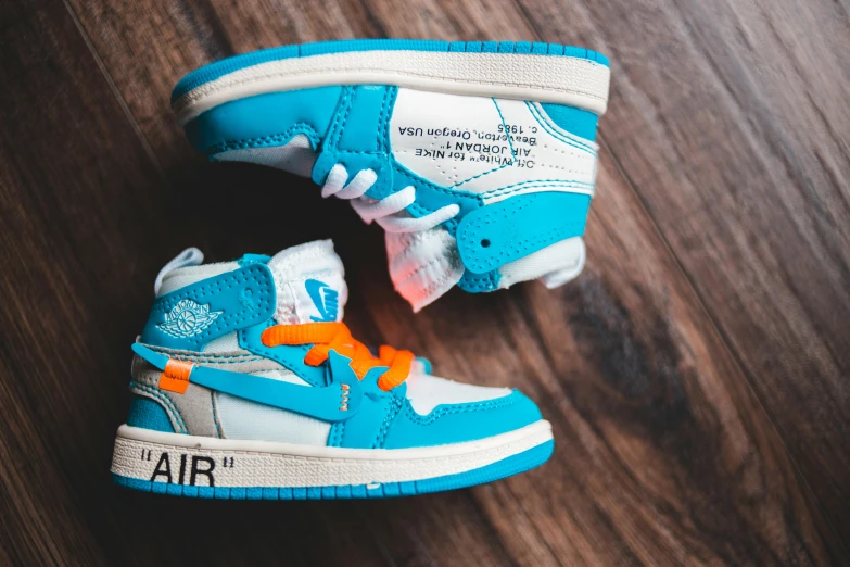 a pair of shoes sitting on top of a wooden floor, unsplash, hyperrealism, orange and cyan paint decals, “air jordan 1, uniform off - white sky, mini model