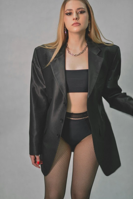 a woman in a black suit posing for a picture, an album cover, inspired by Elsa Bleda, trending on pexels, renaissance, bra and shorts streetwear, silky garment, fishnet clothes, subject detail: wearing a suit
