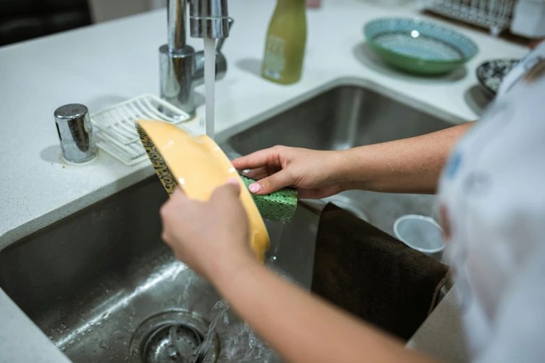 a person using a brush to clean a sink, by Jacqui Morgan, unsplash, with yellow cloths, jill stingray, ready to eat, profile image