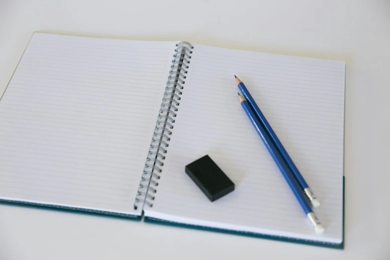 a notebook with a pencil and eraser next to it, by Robbie Trevino, pexels, square lines, fan favorite, rectangular, shot on sony a 7