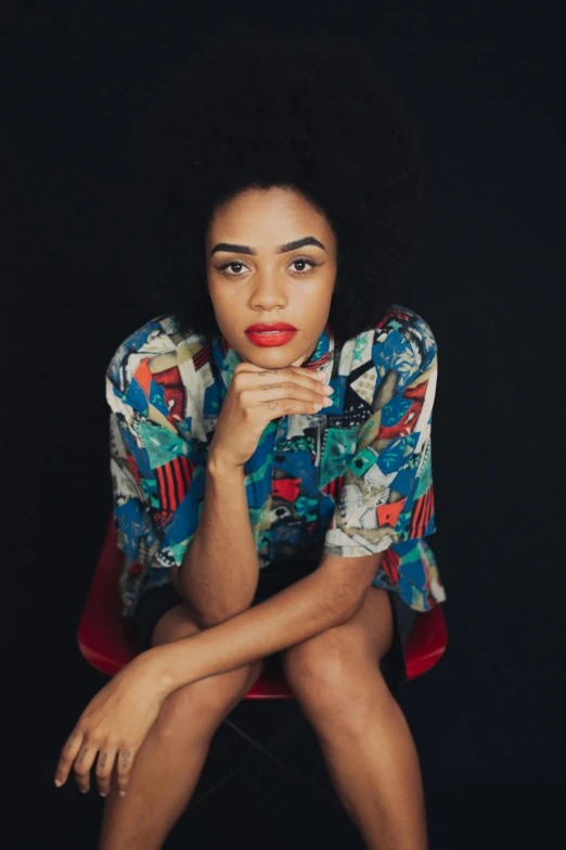 a woman sitting on top of a red chair, tessa thompson inspired, infp young woman, square, with hawaiian shirt