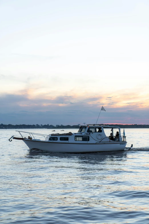 a white boat floating on top of a body of water, happening, at the sunset, touring, on the bow, lit up