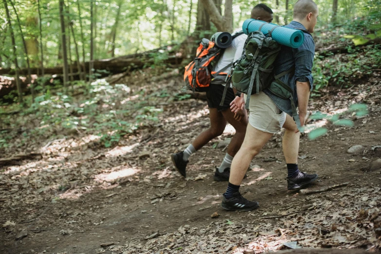 a couple of people that are walking in the woods, pexels, renaissance, white shorts and hiking boots, avatar image, a man wearing a backpack, head down