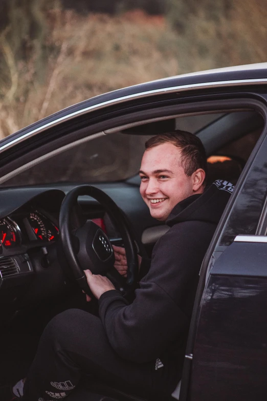 a man sitting in the driver's seat of a car, by Jacob Toorenvliet, discord profile picture, smiling male, ready to model, around 20 yo