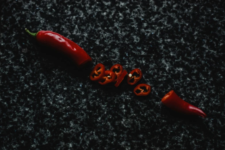 a couple of chili peppers sitting on top of a table, by Elsa Bleda, pexels contest winner, hyperrealism, lying scattered across an empty, dividing it into nine quarters, abstract claymation, chilly dark mood