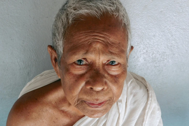 a close up of a person wearing a white shirt, a character portrait, unsplash, hyperrealism, cambodia, the look of an elderly person, white sarong, she is facing the camera