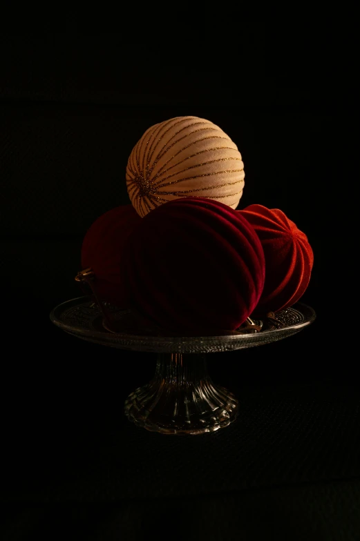 a cake sitting on top of a glass cake plate, inspired by Joseph Wright of Derby, unsplash, baroque, spheres, red fabric, dim lit, rendered in corona