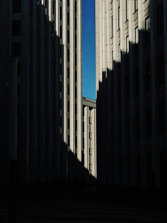 a couple of tall buildings sitting next to each other, an album cover, unsplash contest winner, brutalism, great light and shadows”, ((monolith)), alley, hyperdetailed photo