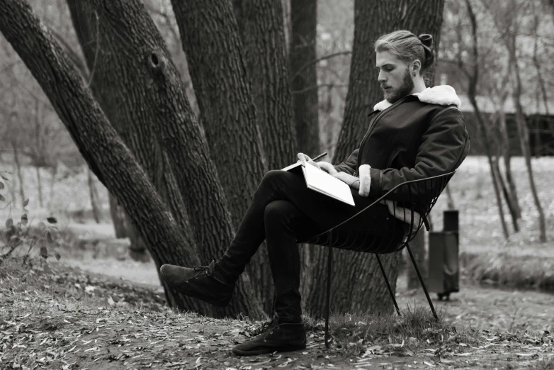 a man sitting in a chair reading a book, a black and white photo, by Emma Andijewska, pexels, visual art, in the park, in the design of eliot kohek, kramskoi 4 k, cai xukun