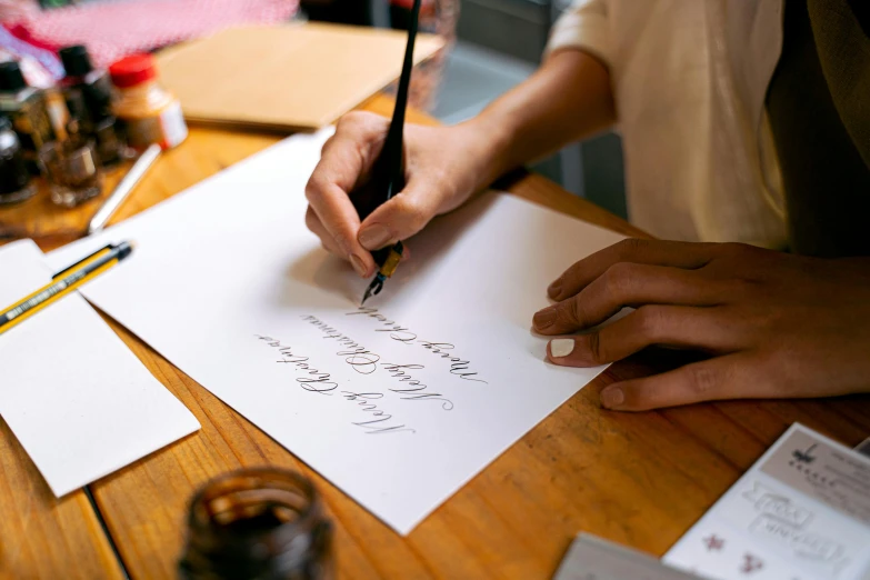 a person sitting at a table writing on a piece of paper, pexels contest winner, academic art, calligraphic poetry, uppercase letter, banner, thumbnail