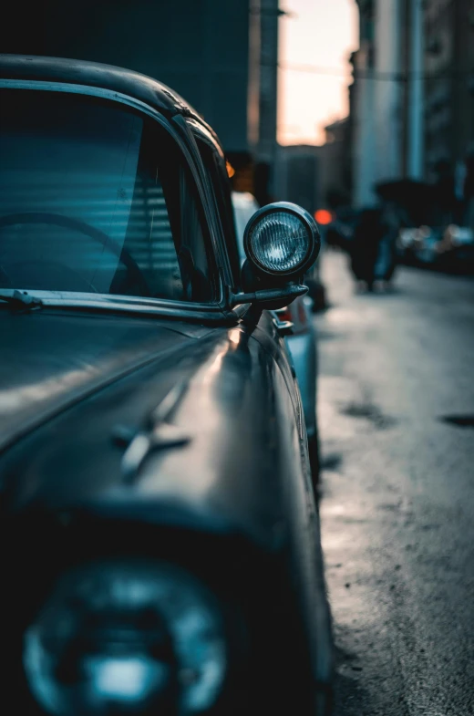 a black car parked on the side of the road, pexels contest winner, photorealism, car lights, vintage photo, city depth of field, waist up