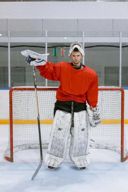 a man standing in front of a goalie net, a colorized photo, pexels contest winner, confident stance, looking to camera, college, hasselblade wide shot