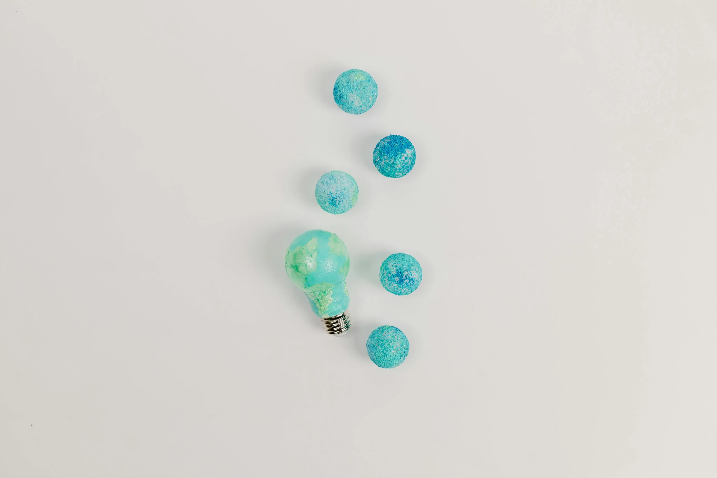 a light bulb sitting on top of a white table, inspired by Évariste Vital Luminais, process art, blue and green, candy decorations, detailed product photo, sea foam