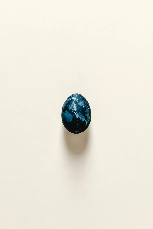 a blue stone sitting on top of a white surface, by Jacob Toorenvliet, ivory and black marble, top - down photograph, egg, illustration