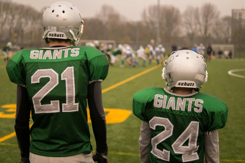 a couple of young men standing next to each other on a field, by Adam Marczyński, pexels contest winner, football armor, giants, green and white, photo realistic”