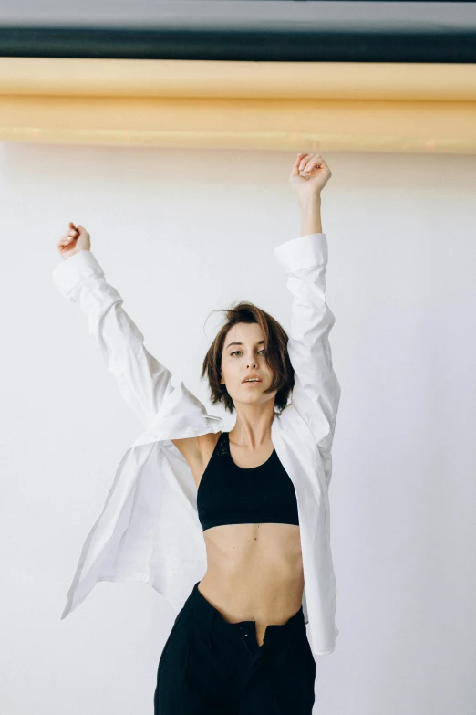 a woman holding a surfboard above her head, trending on unsplash, arabesque, wearing a track suit, in white room, fists in the air, anatomically perfect