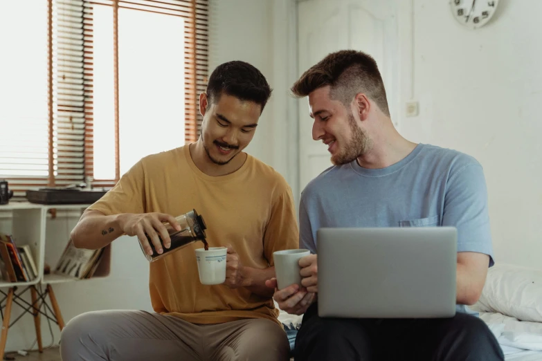 two men sitting on a bed looking at a laptop, pexels contest winner, aussie baristas, is ((drinking a cup of tea)), two men hugging, avatar image