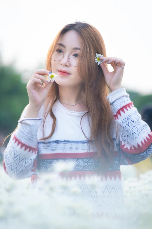 a woman standing in a field of white flowers, inspired by Kim Jeong-hui, pexels contest winner, with square glasses, wearing casual sweater, soft red hair, beautiful young asian woman