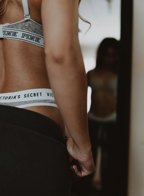 a woman in a white bra top and black leggings, by Sebastian Vrancx, pexels contest winner, victoria's secret, lower back, trending on vsco, black and grey