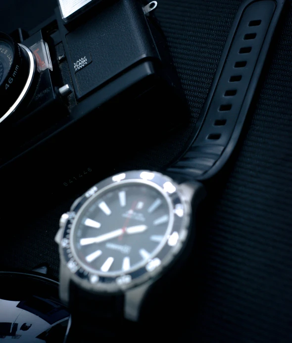 a watch sitting on top of a table next to a camera, by Adam Marczyński, silver sports watch, various posed, f / 2 0, morning detail