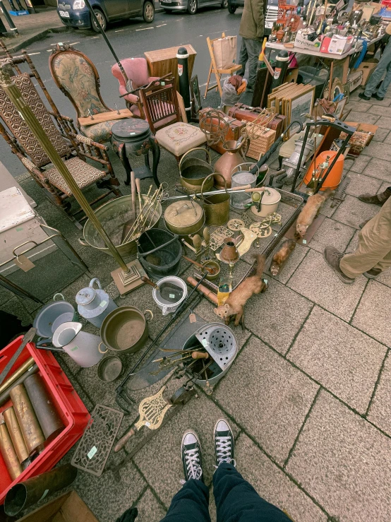 a person standing in front of a table full of antiques, an album cover, by Niko Henrichon, unsplash, assemblage, street vendors, high view, pots and pans, ultra realistic 8k octan photo