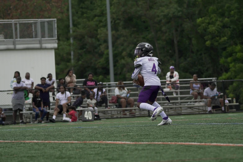 a football player running with the ball during a game, by Ben Thompson, unsplash, renaissance, a purple and white dress uniform, low quality footage, alexis franklin, purple and black