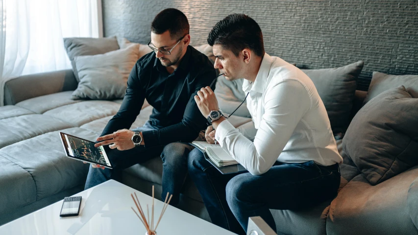 two men sitting on a couch looking at a laptop, pexels contest winner, 9 9 designs, in style of kyrill kotashev, functional and elegant look, avatar image