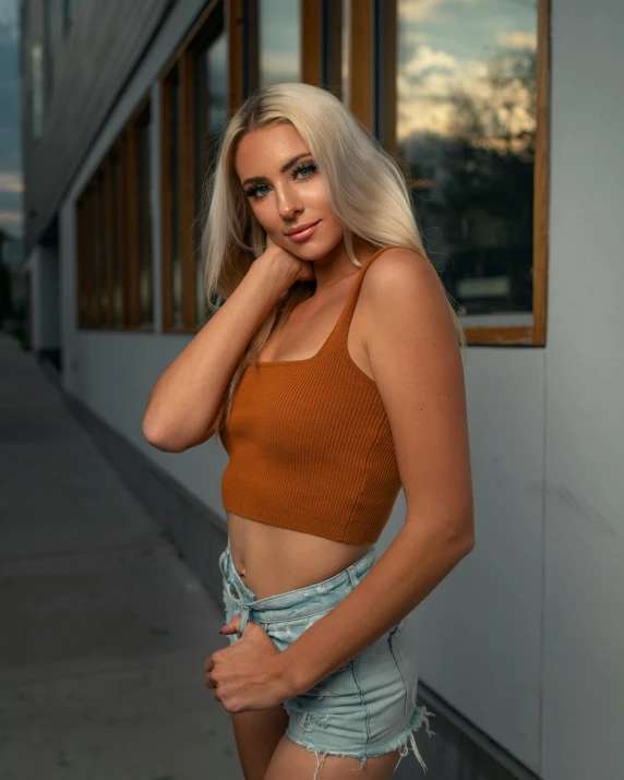 a woman posing for a picture in front of a building, by Robbie Trevino, wearing crop top, amber glow, profile image, amouranth
