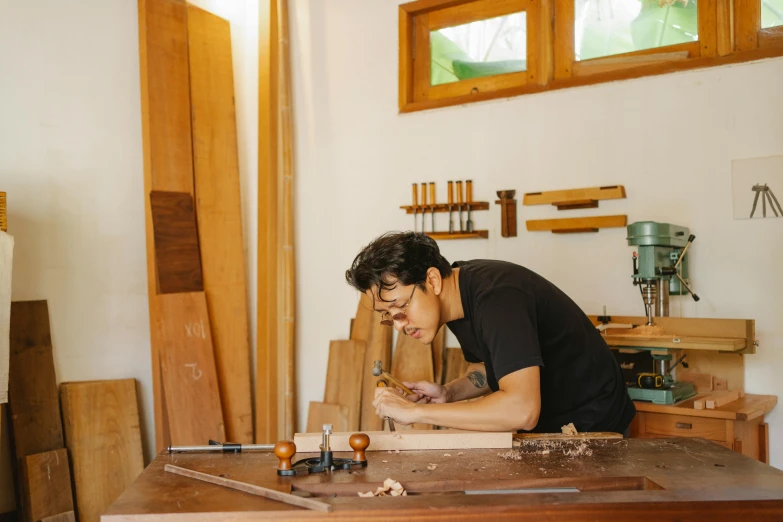 a man sitting at a table working on a piece of wood, by Jessie Algie, pexels contest winner, arts and crafts movement, damien tran, a handsome, ignant, as well as the handyboy