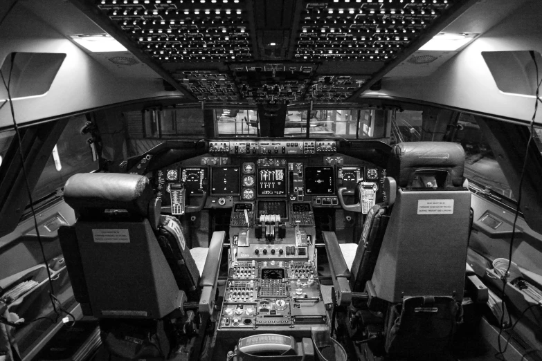 a black and white photo of the cockpit of a plane, by Dan Scott, pexels, high tech space ship interior, late evening, the console is tall and imposing, server