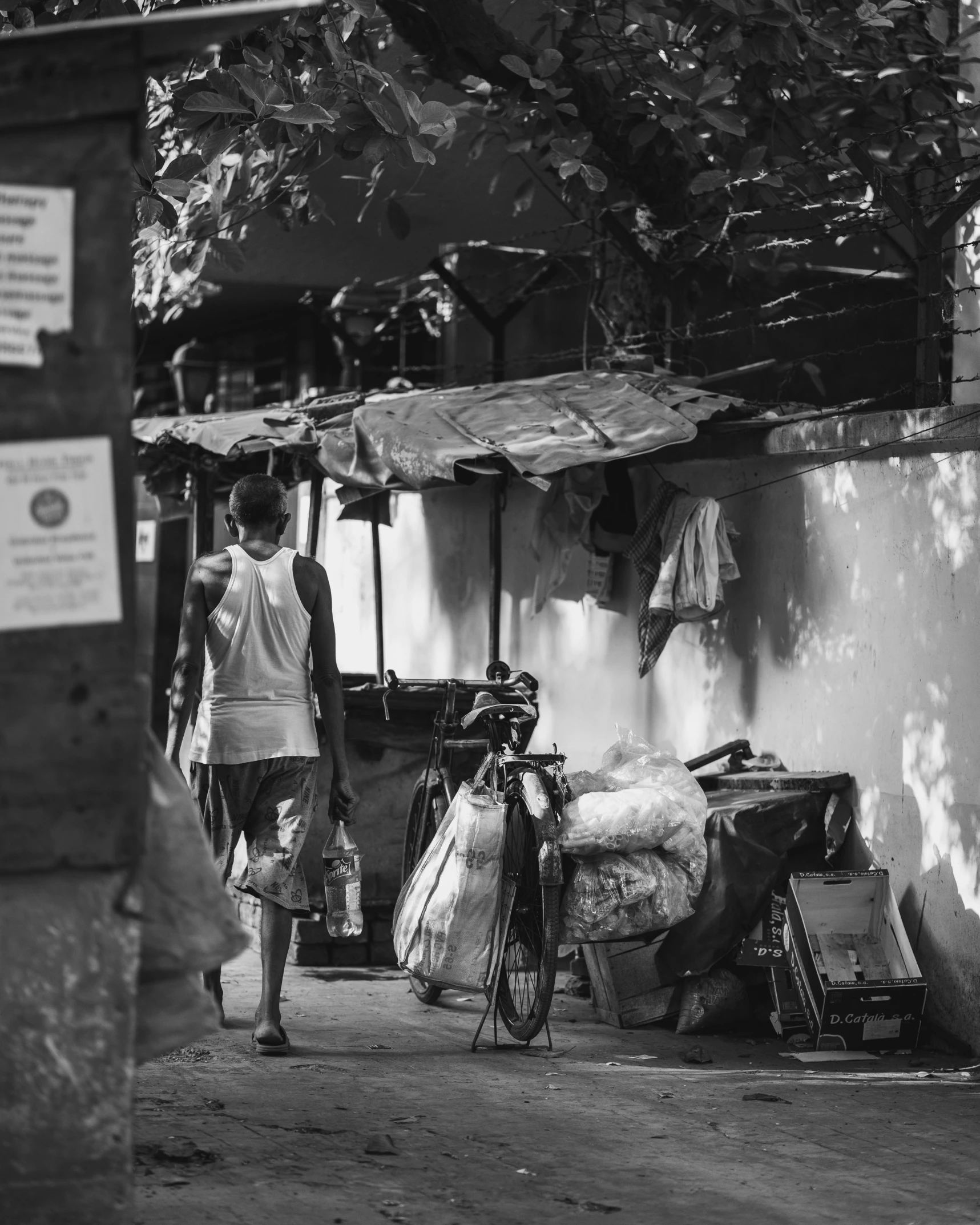 a black and white photo of a man walking down a street, by Joze Ciuha, pexels contest winner, standing in his cluttered garage, summer evening, belongings strewn about, são paulo